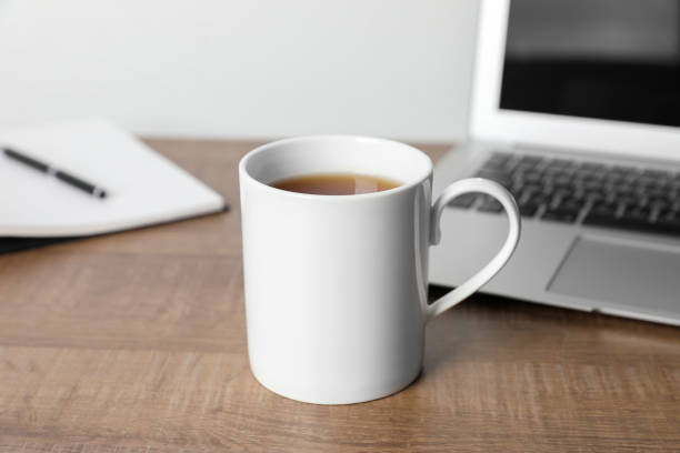 istock White ceramic mug with drink, notebook and laptop on wooden table at workspace 1646846562