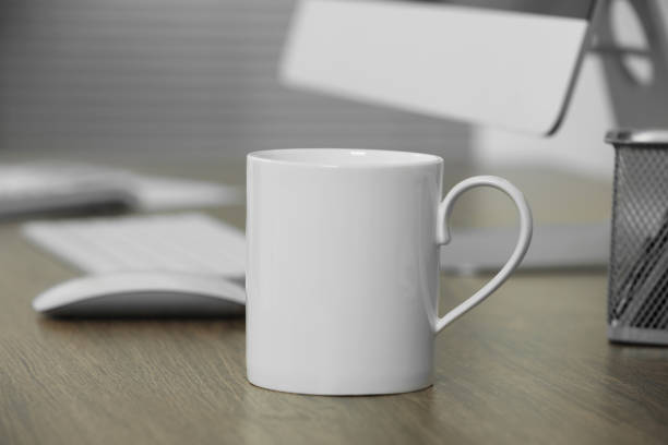 istock White ceramic mug on wooden table at workplace. Mockup for design 1646846574