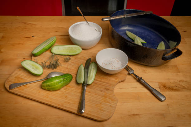 Pickles of home made cucumbers on light wooden table in dirty kitchen