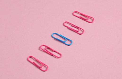 Pink and blue paper clips on pink background. Creative layout. Business concept. Exclusivity, uniqueness. Do not be like everyone else