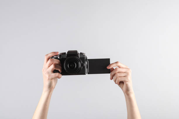 istock Woman's hand holds a modern digital camera with flip screen on gray background 1646849682