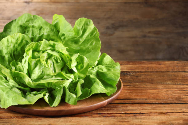 istock Fresh green butter lettuce on wooden table, space for text 1646857772