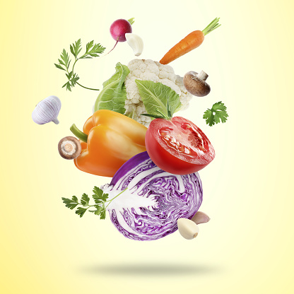 Many fresh vegetables, mushrooms and parsley falling on beige background