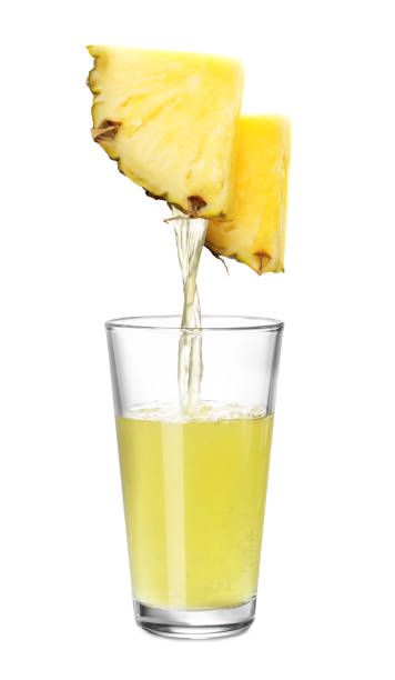Pouring freshly squeezed juice from pineapple into glass on white background