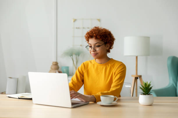 istock African american girl using laptop at home office looking at screen typing chatting reading writing email. Young woman having virtual meeting online chat video call conference Work learning from home 1646894829