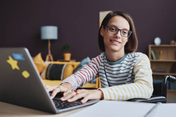 istock Smiling teenage girl with disability using laptop computer at home 1646911702