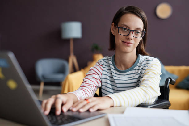 istock Smiling girl with disability using computer at home and looking at camera 1646912212