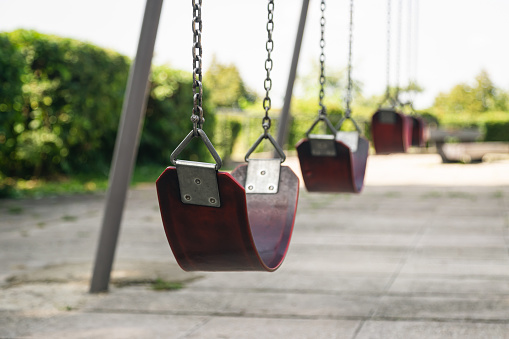Empty chain swing in the park on a blurred background, close up swing seat.