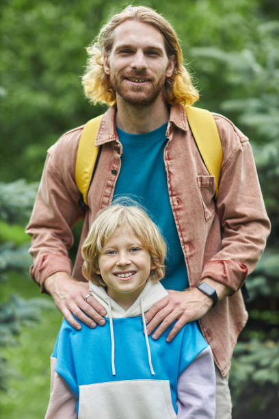 istock Father and son enjoying hiking trip together and looking at camera in forest 1646918059