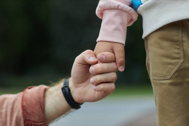 istock Father holding hands with little boy outdoors providing care and security 1646918073