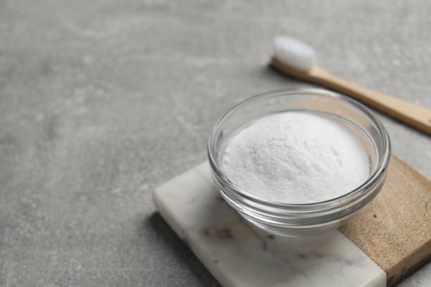 istock Bamboo toothbrush and bowl of baking soda on grey table, closeup. Space for text 1646918637