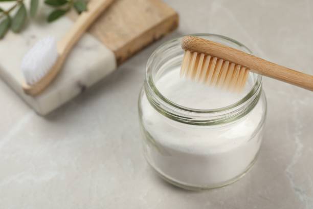 istock Bamboo toothbrush and jar of baking soda on light grey marble table 1646919175