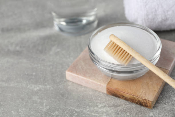 istock Bamboo toothbrush and glass bowl of baking soda on light grey table, space for text 1646920783