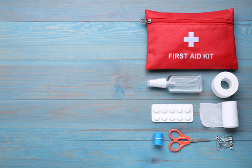 Flat lay composition with first aid kit on blue wooden table, space for text