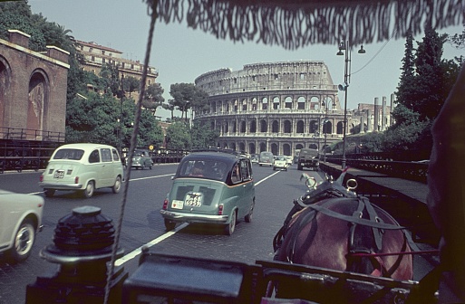 Rome, Lazio, Italy, 1961. Street scene with cars and a horse carriage on a street at the Roman Forum. In the background the Colosseum.
