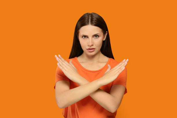 istock Woman with crossed hands on orange background. Stop gesture 1646944803