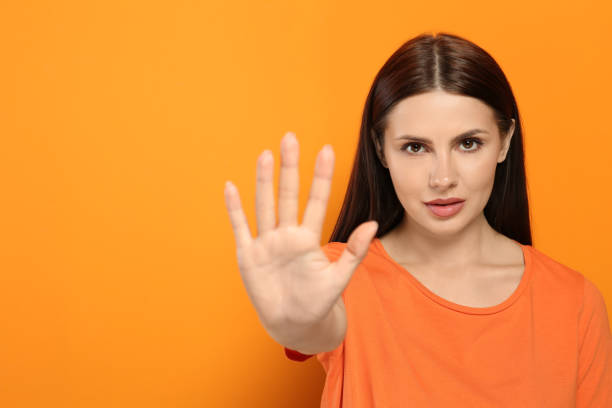 istock Woman showing stop gesture on orange background. Space for text 1646946414