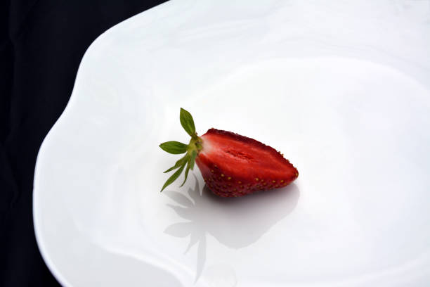 istock Half of a ripe red strawberry on a white shaped plate 1646982597