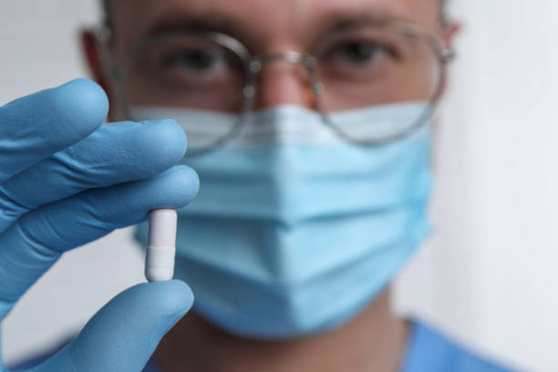 istock Doctor holding pill on light background, selective focus. Space for text 1646984260