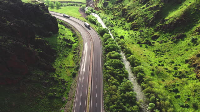 4K aerial drone view of multi lane highway in mountain and green forests area