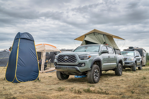 Loveland, CO, USA - August 25, 2023: Pop up privacy shower tent and Toyota Tacoma truck with a roof tent parked at busy campground.
