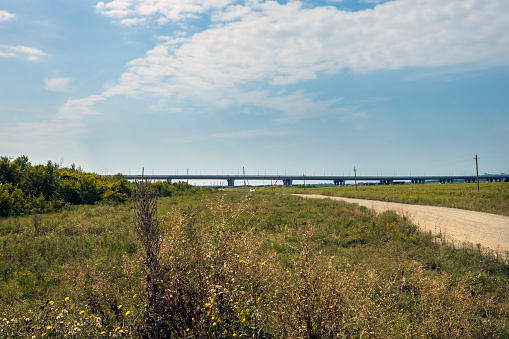 Side view of a bridge and trucks moving along a highway.