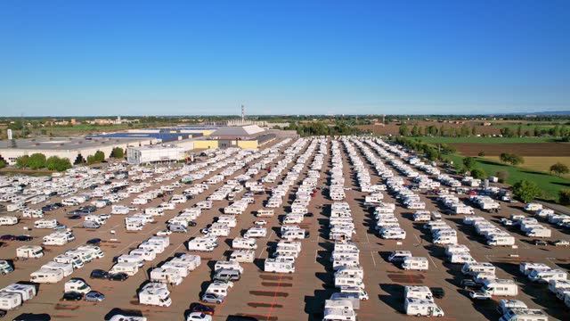 Row of modern campers parked in parking lot view from above at auto in annual exhibition of camper vans (Salone del Camper). Best option for travel feeling free. Parma, Italy - September 17, 2022. 4K