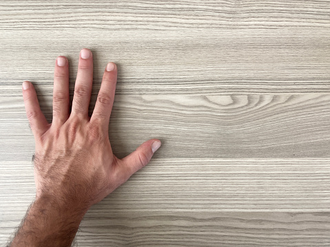 Directly above a male hand on the wooden desk with copy space