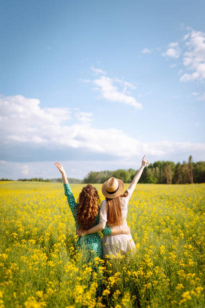 istock Two women have fun in a field among blooming rapeseed. 1647053759