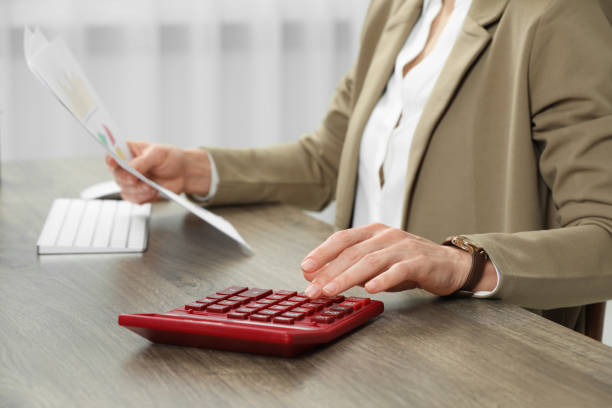 istock Professional accountant using calculator at wooden desk in office, closeup 1647056785