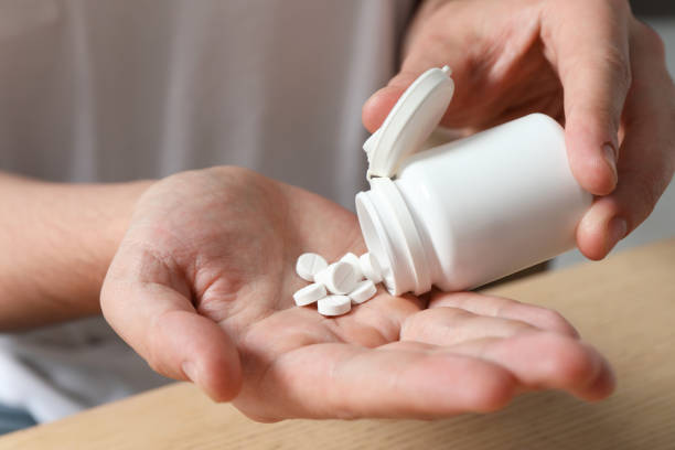 istock Man pouring pills from bottle at table, closeup 1647058104