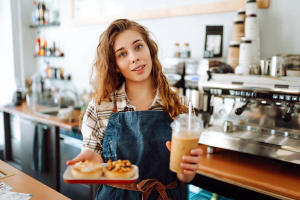 istock Young coffee shop worker holding takeaway drinks and desserts. 1647065137