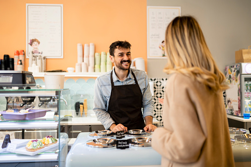 Happy woman buying ice cream at a pastry shop and pointing at the counter - small business concepts