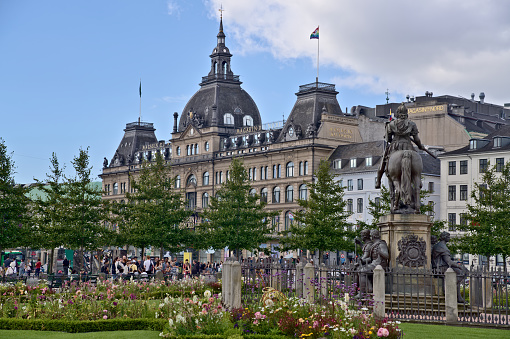 View from the Kings New square on the bronze equestrian statue of Christian V and the Magasin du Nord building with the LGBTQ flag hoisted on the tower in Copenhagen Denmark