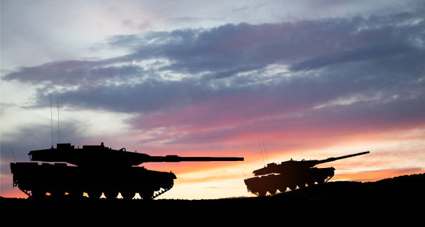 Silhouettes of army tanks at sunset sky background. stock photo