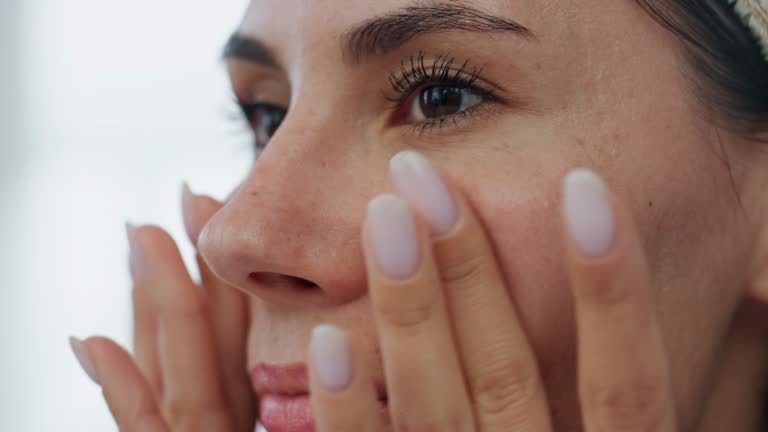 Woman face moisturizing at bath room closeup. Lady applying facial foundation