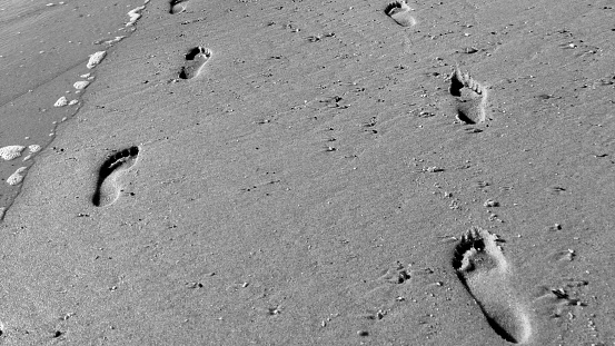 Following footprints on Beach Shore at Low Angle. Black and white scene.