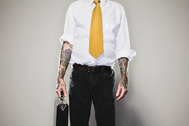 New Professional A business man stands with a briefcase held by one of his tattooed arms, wearing a white collared shirt and tie.  Two forearm sleeve tattoos.  Representing a new generation of modern business standards and style.  Horizontal with copy space. forearm tattoos men stock pictures, royalty-free photos & images