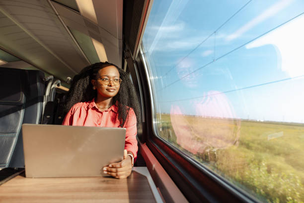 A young African American woman using laptop in train