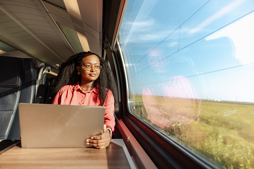 A young African American woman is working on a laptop during a train ride