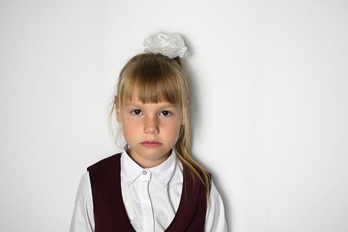 A little girl with a ponytail, a first-grader in a school uniform on a white background. Knowledge Day. September 1. The concept of training.