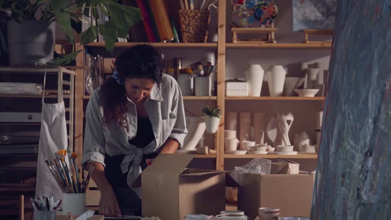 Woman packing pottery products in workshop.