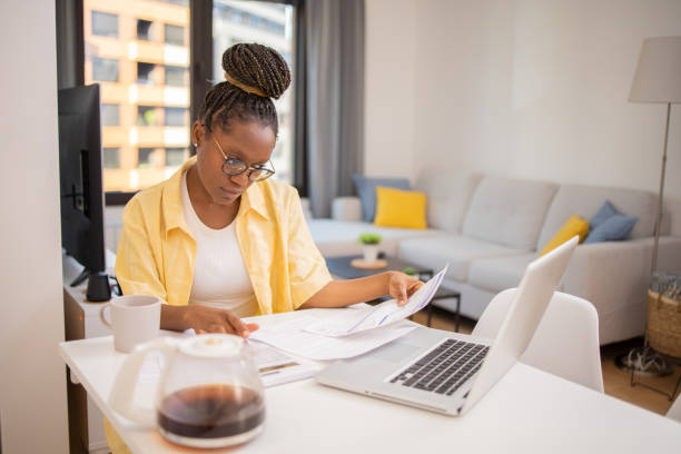 istock Young woman using calculator while going through bills and home finances 1647268395