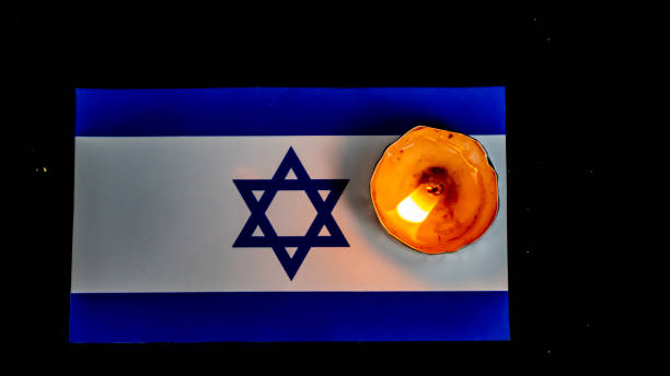 istock Israeli flag and candles burning above it, Holocaust memory day 1647304435