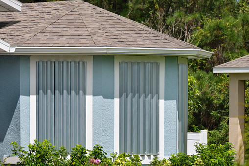 Steel storm shutters for hurricane protection of house windows. Protective measures before natural disaster in Florida.