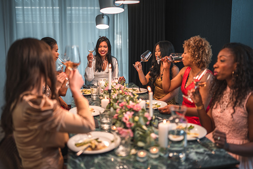 A lively ambiance of a bachelorette dinner where a group of close diverse friends, gather to celebrate the upcoming wedding of their beautiful Asian friend.