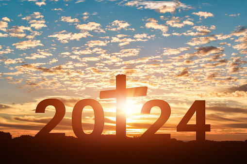 Silhouette of Christian cross with 2024 years at sunset background. Concept of Christians new year 2024