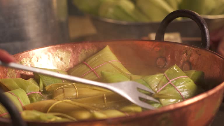 Woman's hands stirring the pamonhas with a fork in a copper pot to cook the pamonha dough better. Collection of themed videos.