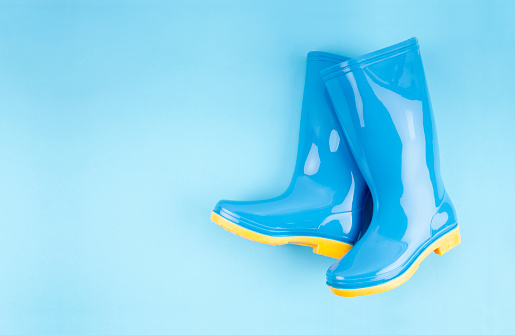A Pair of blue rubber boots on blue background, Top view with empty space for your text.
