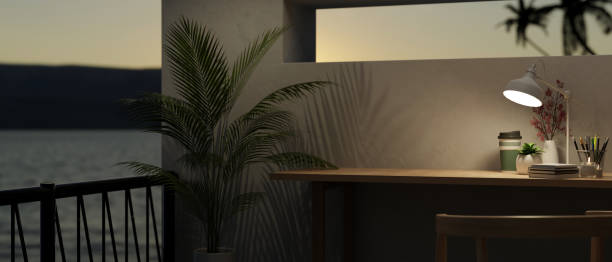 istock Modern workspace at night, copy space on a table and balcony with a beautiful sunset view 1647553157